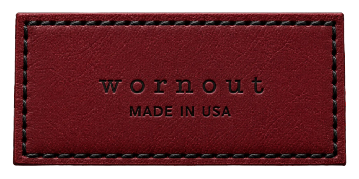 A rectangular red leather patch with black stitching and the debossed brand name 'wornout' along with 'MADE IN USA' text, shown on a white background.
